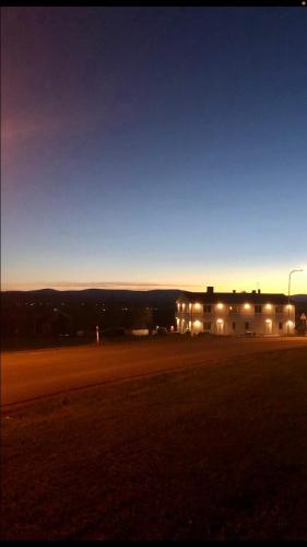 a building with lights on in a field at night at Två rum och kök mellan staden och fjället in Oviken