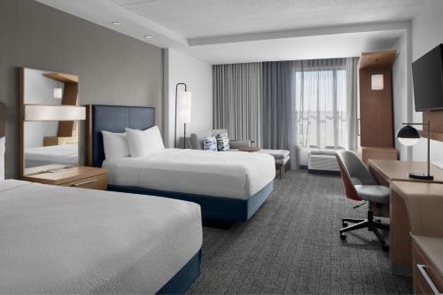 a hotel room with two beds and a desk at Courtyard by Marriott Charleston Summerville in Summerville