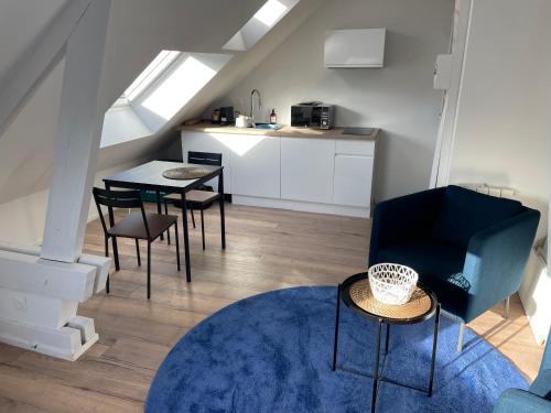 Una sala de estar con mesa y sillas y una cocina. en Studio 302 - Hyper Centre - Intégralement rénové - Toutes commodités à pied, en Saint-Nazaire