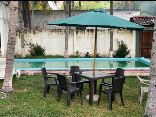 einen Tisch mit Stühlen und einen Sonnenschirm neben einem Pool in der Unterkunft Cielito Lindo Rancho in San Diego