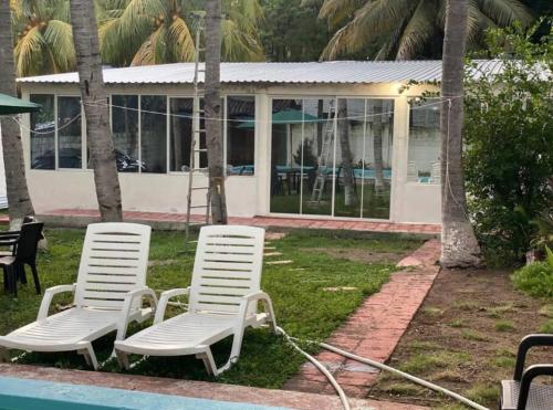 zwei weiße Gartenstühle neben einem Pool in der Unterkunft Cielito Lindo Rancho in San Diego