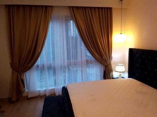 una camera con letto e finestra con tende di 1 BDR 74SQM Luxury APT with separate Bedroom Pool, Gym, Balcony, King Size Bed Cantonments a Accra