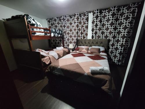 um quarto com uma cama e um beliche com uma colcha em Departamento Duplex con Terraza em Cuenca