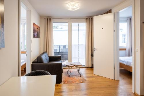 ein Wohnzimmer mit einem Sofa, einem Stuhl und einem Bett in der Unterkunft Modern apartment w/ cozy balcony near city center in Wien