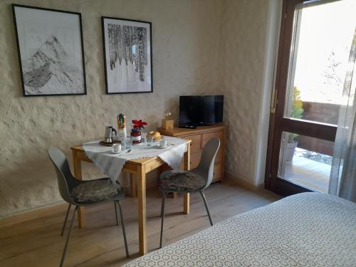 a room with a table with chairs and a television at Fradusta 213 in San Martino di Castrozza