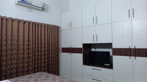 a bedroom with a television and a white cabinet at Niks home stay - A in Trichūr