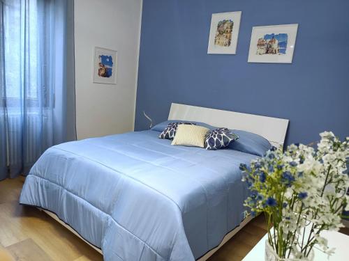 ein blaues Schlafzimmer mit einem Bett mit blauer Bettwäsche und Blumen in der Unterkunft Amalphia Home in Salerno