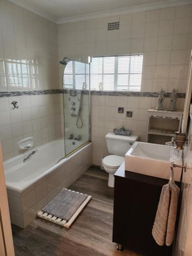 a bathroom with a tub and a toilet and a sink at Rosewood Guest Cottage in Vryheid