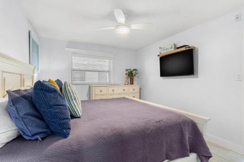 a bedroom with a bed with a ceiling fan and a tv at Beach Oasis - No Storm Damage & Guest Ready! Come Enjoy the Heated Pool & Relax at the Beach! in Clearwater Beach