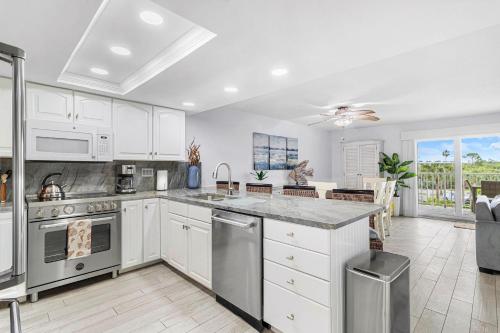 a kitchen with white cabinets and stainless steel appliances at Beach Oasis - No Storm Damage & Guest Ready! Come Enjoy the Heated Pool & Relax at the Beach! in Clearwater Beach