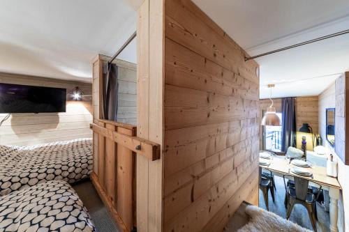 Cette chambre est dotée d'un mur en bois, d'un lit et d'un bureau. dans l'établissement Le Cocooning - IMMODREAMS - Avoriaz, à Avoriaz