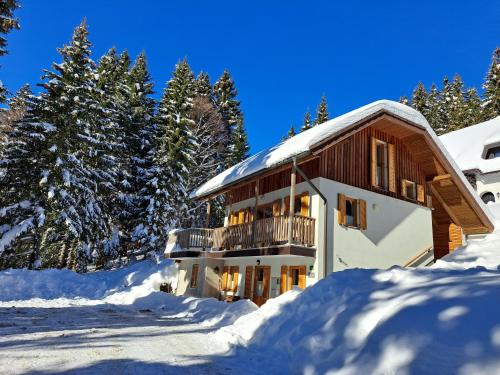 un edificio cubierto de nieve con árboles en el fondo en Chalet Harmony Rogla - apartment, en Zreče