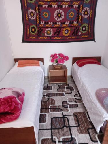 two beds in a room with a rug on the wall at Sayfi Guesthouse in Dushanbe