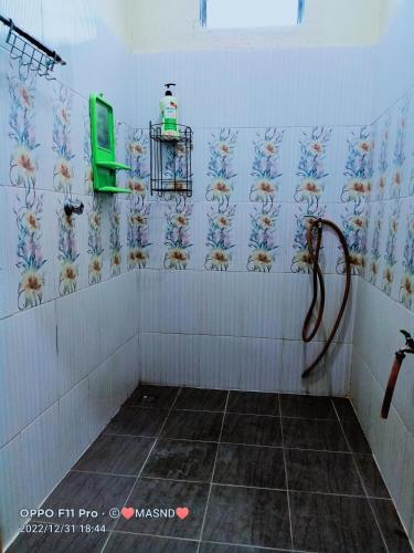a bathroom with a shower with a green tv on the wall at Tunas Homestay & Chalet in Pantai Cenang