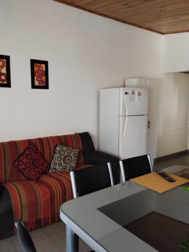 a living room with a couch and a table and a refrigerator at Alojamiento Alem in General Alvear