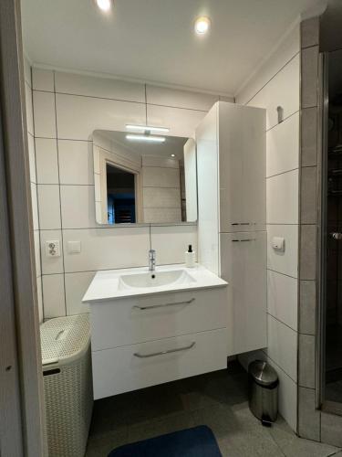 a white bathroom with a sink and a mirror at Dārzu ielas apartamenti in Rēzekne