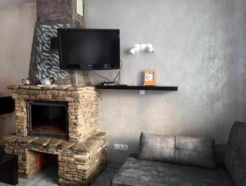 a living room with a fireplace with a flat screen tv at Apartaments Gory in Niedzica Zamek