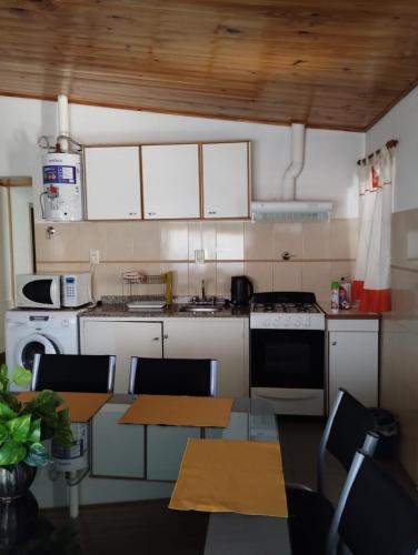 kuchnia z białymi urządzeniami oraz stołem i krzesłami w obiekcie Alojamiento Alem w mieście General Alvear
