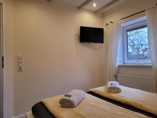 2 camas en una habitación con TV en la pared en Ferienhaus Wind, en Struckum
