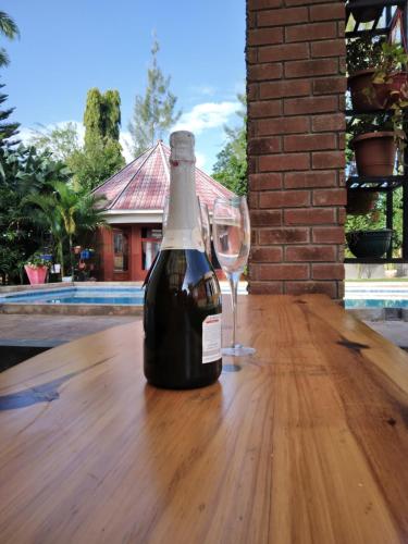 uma garrafa de vinho sentada numa mesa de madeira com um copo em Sprunger Avenue - tulia homes em Moshi