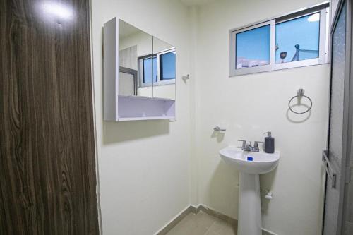 Baño blanco con lavabo y espejo en Casa Bita Morales CASA 101, en Las Canoas