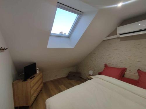 a attic bedroom with a bed and a window at Gîte Le Clos Controis in Contres