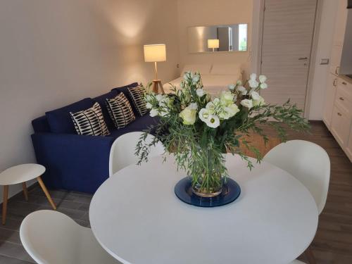 a white table with a vase of flowers on it at Home 101 in Calasetta