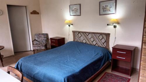 um quarto com uma cama azul e duas mesas e uma cadeira em Lo de Tini em Gualeguaychú