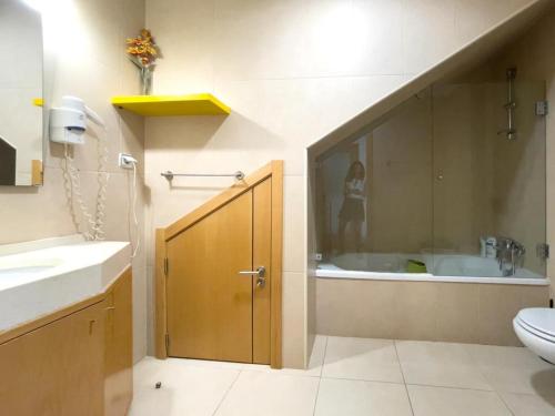 a bathroom with a sink and a tub with a person standing in the shower at Magnifique Duplex avec piscine en bord de mer in Olhos de Água