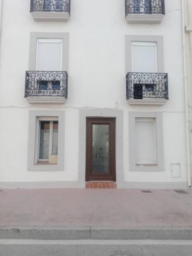 un bâtiment avec des fenêtres bleues et blanches et une porte dans l'établissement Studio équipé 2 personnes, Port la Nouvelle centre, à Port-la-Nouvelle