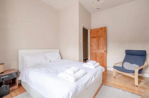 um quarto com uma cama branca e uma cadeira azul em Stylish 2 Bed Garden Flat in Zone 1 Central London em Londres