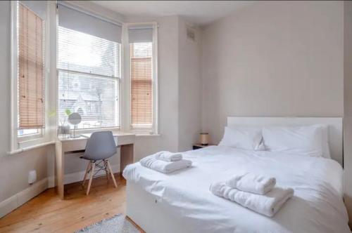 a bedroom with a white bed with towels on it at Stylish 2 Bed Garden Flat in Zone 1 Central London in London