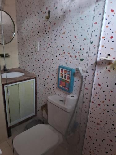 a bathroom with a toilet and a wall covered in confetti at Casa do Mar in Guarapari