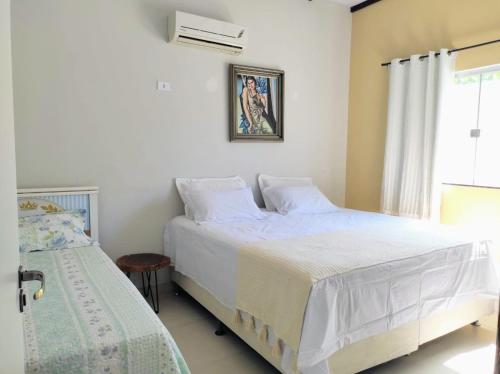 - une chambre blanche avec 2 lits et une fenêtre dans l'établissement Casa de ferias paraíso, à Santa Cruz Cabrália