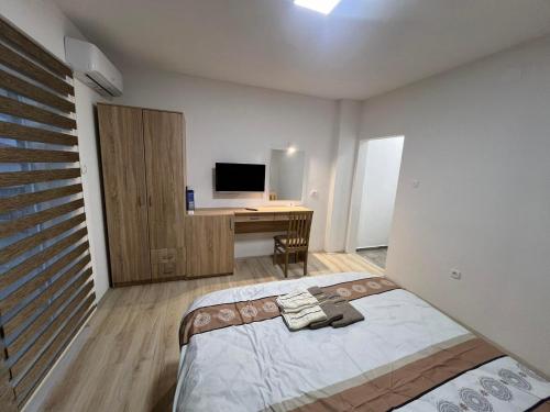 a bedroom with a bed and a desk with a television at Royal Stars Apartments in Strumica