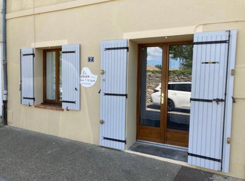 un bâtiment avec des portes bleues et une voiture sous la fenêtre dans l'établissement Apartloisir, à Malaucène