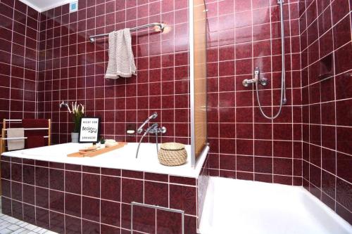 a red tiled bathroom with a tub and a sink at KU01-RI Apartment in Kulmbach EG in Kulmbach