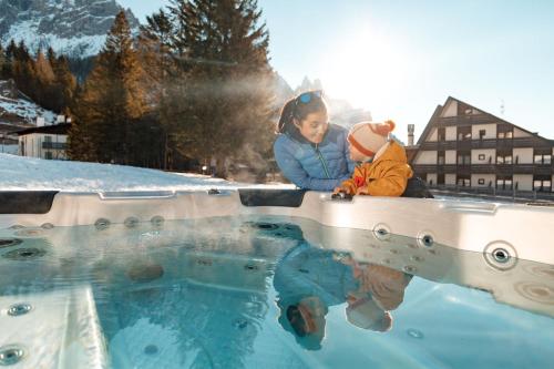 a woman and a child looking at a pool of water at Ski Residence in San Martino di Castrozza