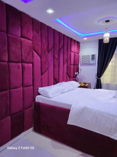 ein Schlafzimmer mit einer rosa gepolsterten Wand neben einem Bett in der Unterkunft O'ffidaus J Luxury Hotel And Suites Int Ltd in Benin City