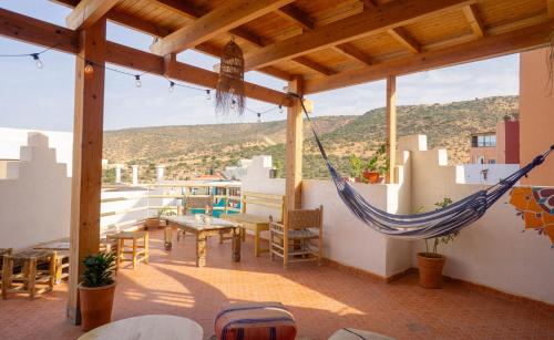 eine Veranda mit einer Hängematte sowie einem Tisch und Stühlen in der Unterkunft Arima Surf House in Tamraght Ouzdar