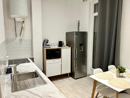 une cuisine avec un réfrigérateur en acier inoxydable et une table dans l'établissement Lumineux 2 pièces - centre-ville climatisé - netflix prime canal - bien placé, à Marseille