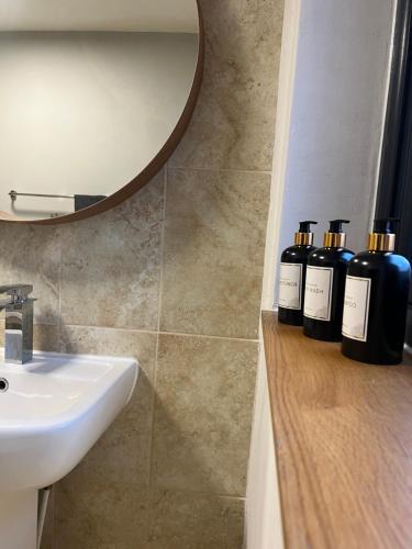a bathroom with a sink and four bottles of soap at Hempshill Lane holiday home in Nottingham