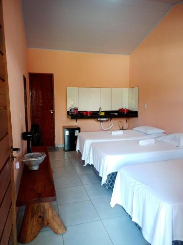 a hotel room with two beds and a table at Pousada Verde do Mato in Pirenópolis