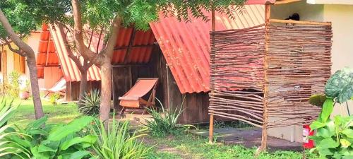 a building with a red roof and a bench at Cabanas Rusticas in Las Peñitas