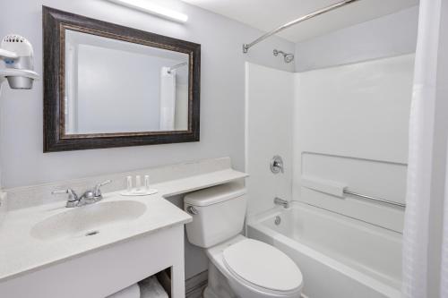 a white bathroom with a sink and a toilet at Days Inn & Suites by Wyndham Colonial in Williamsburg