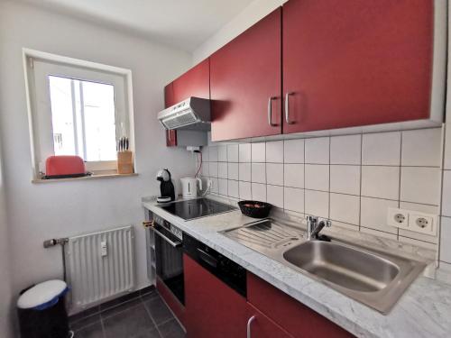 a kitchen with red cabinets and a sink at Komfortable 2-Zimmer-Ferienwohnung am Kurpark in Bad Kreuznach