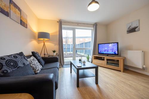 ein Wohnzimmer mit einem Sofa und einem TV in der Unterkunft Beautiful 4 Bed House in Manchester Free Parking in Manchester