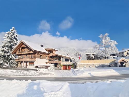 a lodge in the snow with snow covered mountains at Aparthotel Buchauer-Tirol in Thiersee