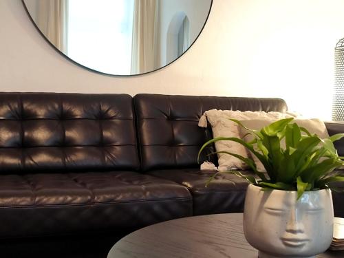 a brown leather couch with a table and a mirror at CozyHome Signature Palisady Apartment in Bratislava
