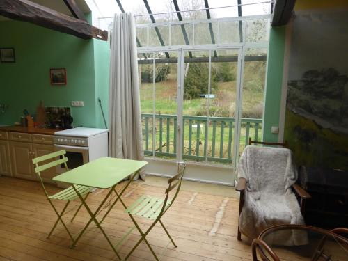 ジヴェルニーにあるLes Buissonnetsのテーブルと椅子、窓が備わる客室です。
